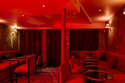 Miniature Location salle Paris 2 (Paris) - Culot #7 Salle intimiste éclairée de lumières rouges, avec canapés, petites tables rondes et rideaux sombres en arrière-plan.