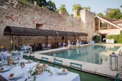 Salle lumineuse avec grandes baies vitrées, tables rondes en métal et lustres suspendus sous un plafond décoré.