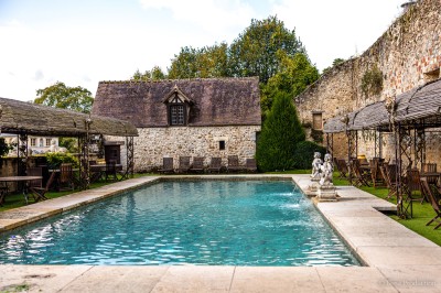 Salle lumineuse avec grandes baies vitrées, tables rondes en métal et lustres suspendus sous un plafond décoré.