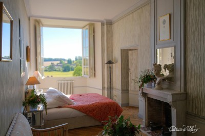 Salle lumineuse avec grandes baies vitrées, tables rondes en métal et lustres suspendus sous un plafond décoré.