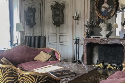 Salle lumineuse avec grandes baies vitrées, tables rondes en métal et lustres suspendus sous un plafond décoré.