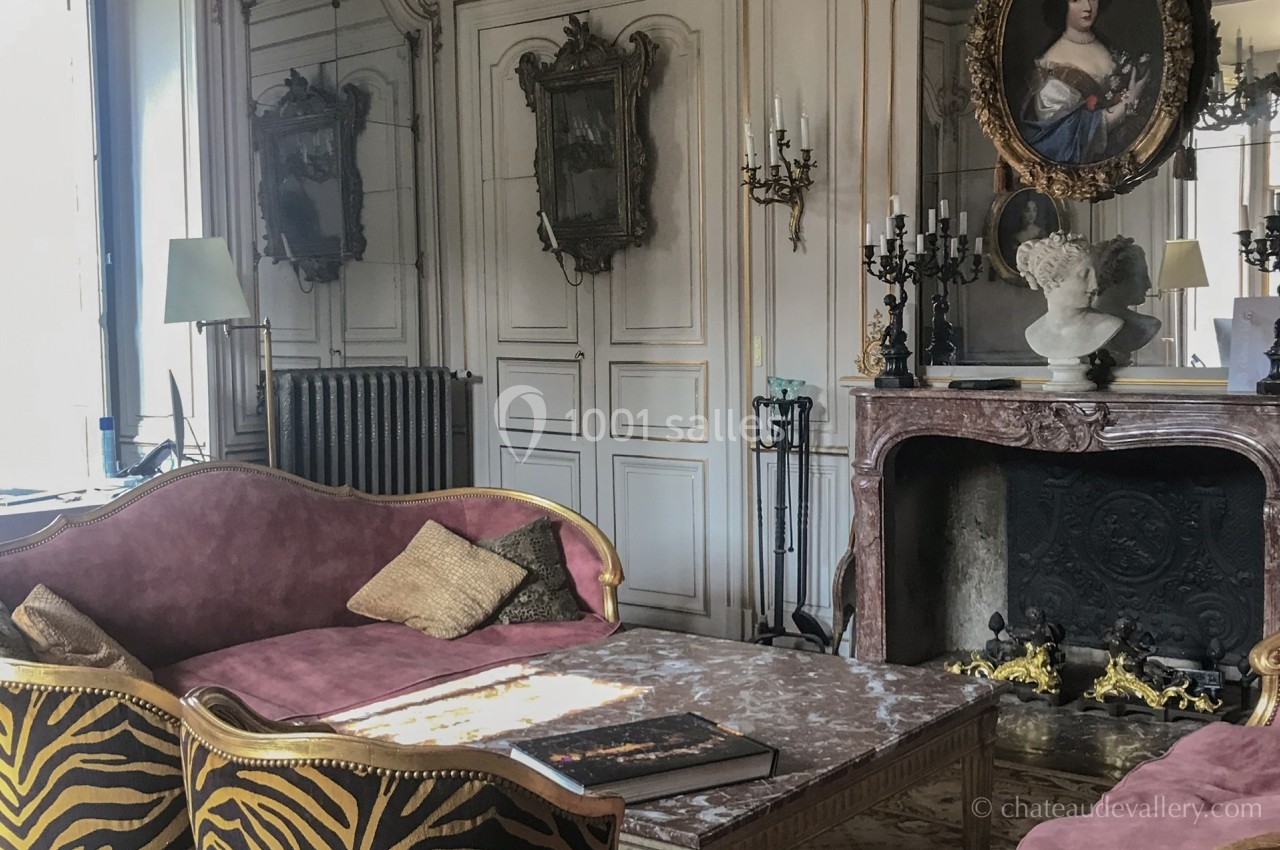 Salon élégant avec canapé en velours, cheminée ornée, miroir ancien et décoration classique.