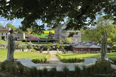 Salle lumineuse avec grandes baies vitrées, tables rondes en métal et lustres suspendus sous un plafond décoré.