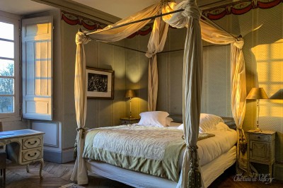 Salle lumineuse avec grandes baies vitrées, tables rondes en métal et lustres suspendus sous un plafond décoré.