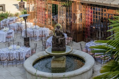 Salle lumineuse avec grandes baies vitrées, tables rondes en métal et lustres suspendus sous un plafond décoré.