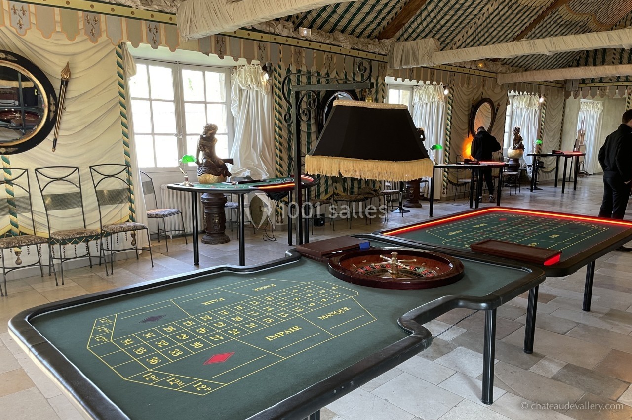 Salle de jeux avec une table de roulette, des chaises et une décoration intérieure élégante et lumineuse.
