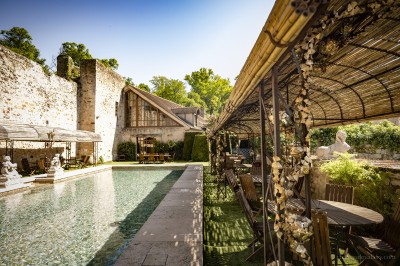 Salle lumineuse avec grandes baies vitrées, tables rondes en métal et lustres suspendus sous un plafond décoré.