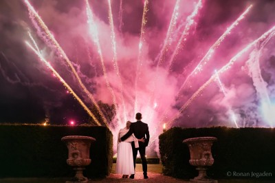 Un groupe de femmes en robes élégantes réagit avec joie face à une mariée dans une pièce décorée.