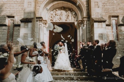 Un groupe de femmes en robes élégantes réagit avec joie face à une mariée dans une pièce décorée.