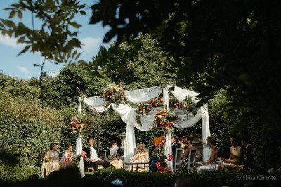 Un groupe de femmes en robes élégantes réagit avec joie face à une mariée dans une pièce décorée.