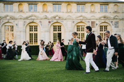 Un groupe de femmes en robes élégantes réagit avec joie face à une mariée dans une pièce décorée.
