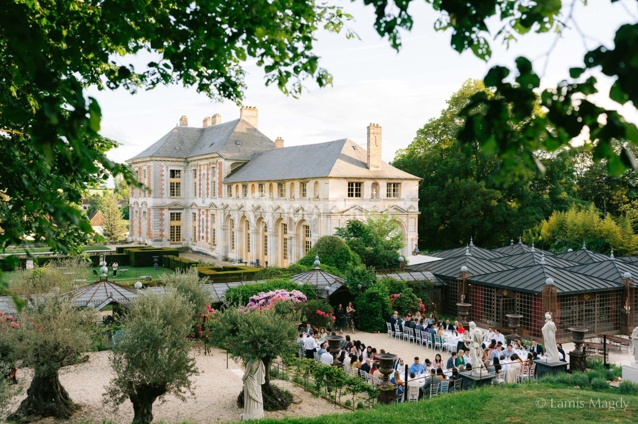 Manoir historique entouré de jardins verdoyants avec des invités assis lors d'un événement en plein air.