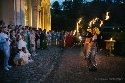 Un groupe de femmes en robes élégantes réagit avec joie face à une mariée dans une pièce décorée.
