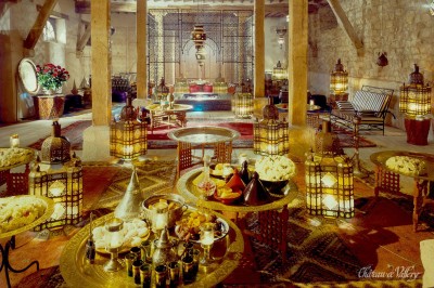 Un groupe de femmes en robes élégantes réagit avec joie face à une mariée dans une pièce décorée.