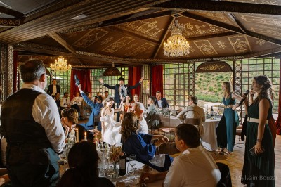 Un groupe de femmes en robes élégantes réagit avec joie face à une mariée dans une pièce décorée.