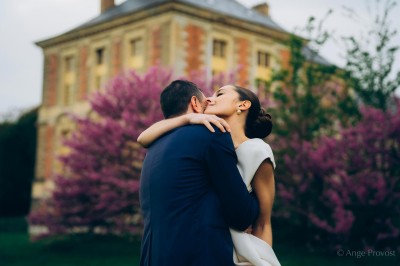 Un groupe de femmes en robes élégantes réagit avec joie face à une mariée dans une pièce décorée.