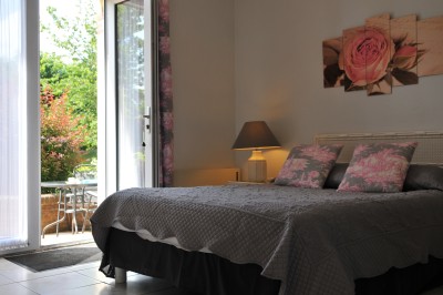 Piscine intérieure avec grandes baies vitrées donnant sur un jardin, entourée de plantes et d'une statue décorative.