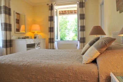 Piscine intérieure avec grandes baies vitrées donnant sur un jardin, entourée de plantes et d'une statue décorative.