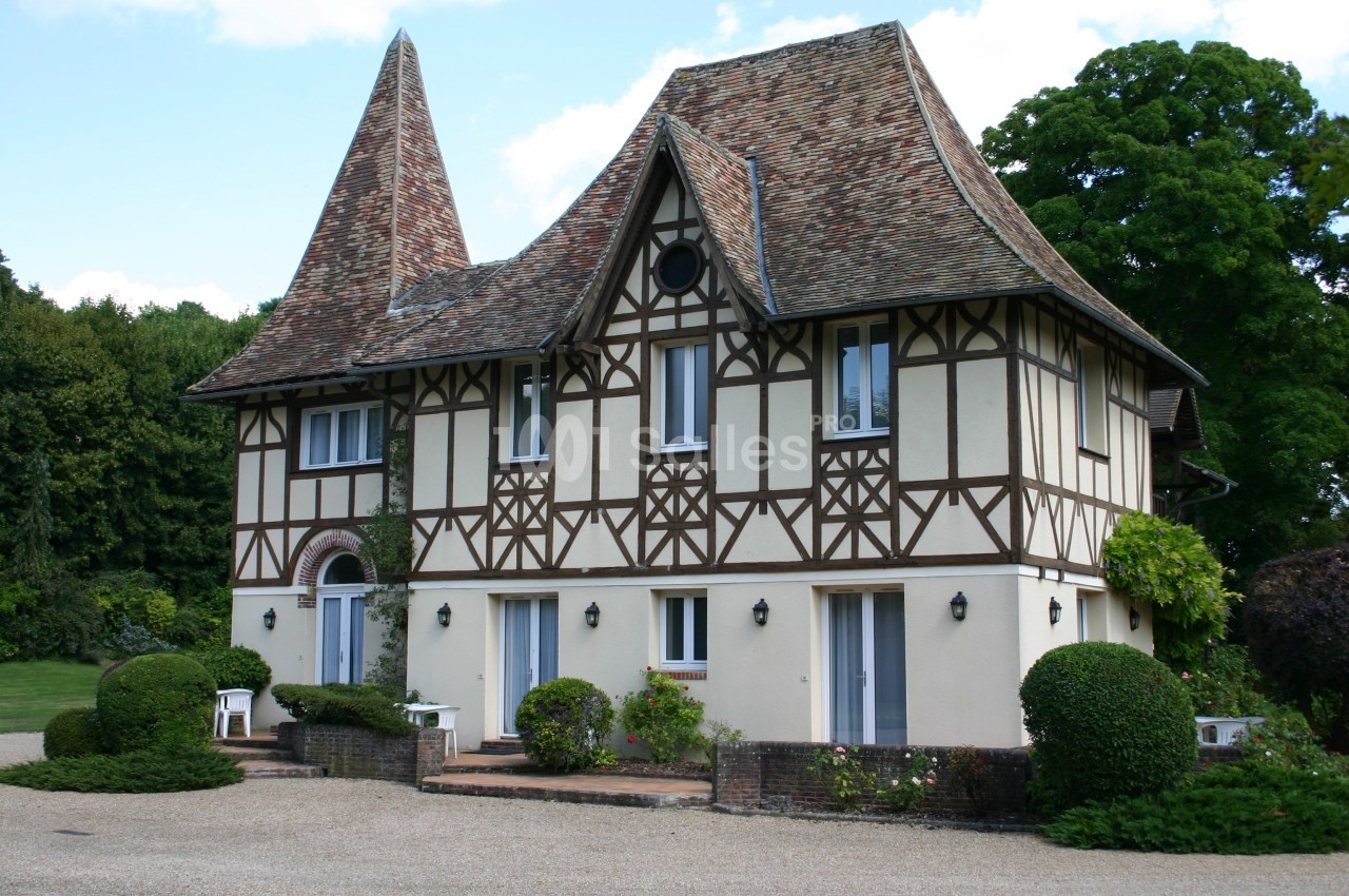 Maison à colombages avec toit en tuiles, entourée de végétation et située dans un cadre verdoyant.