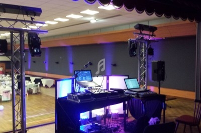 Équipement de DJ installé dans une salle de réception avec tables dressées en arrière-plan.