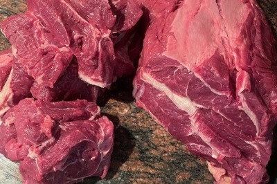 Burger au saumon fumé avec laitue, tomate et sauce, posé sur une table en marbre avec citron vert et herbes en arrière-plan.