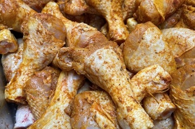 Burger au saumon fumé avec laitue, tomate et sauce, posé sur une table en marbre avec citron vert et herbes en arrière-plan.