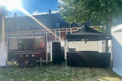 Burger au saumon fumé avec laitue, tomate et sauce, posé sur une table en marbre avec citron vert et herbes en arrière-plan.