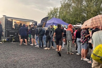 Burger au saumon fumé avec laitue, tomate et sauce, posé sur une table en marbre avec citron vert et herbes en arrière-plan.