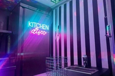 Burger au saumon fumé avec laitue, tomate et sauce, posé sur une table en marbre avec citron vert et herbes en arrière-plan.