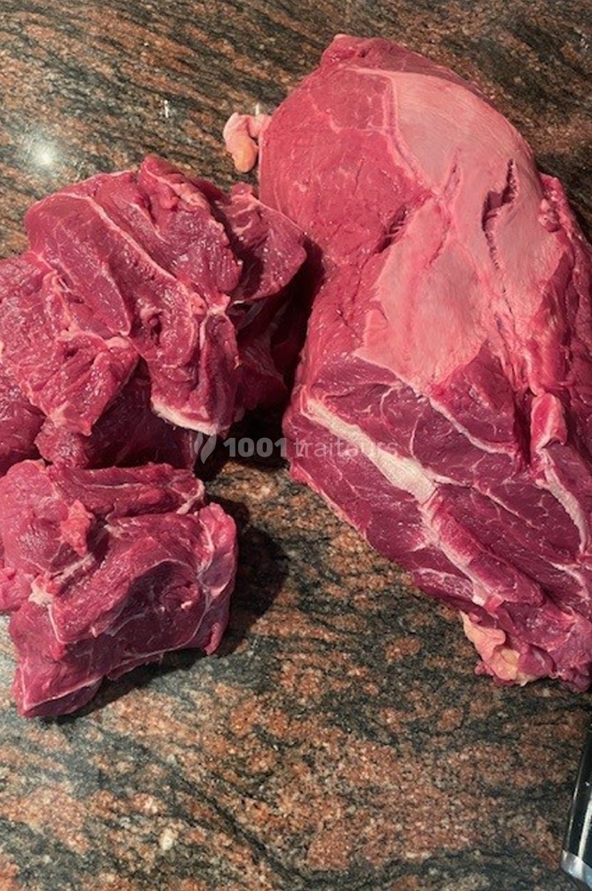 Morceaux de viande rouge crue posés sur un plan de travail en pierre.