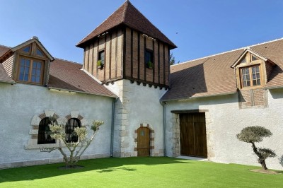 Vue aérienne d'une campagne verdoyante avec des champs, des arbres, une rivière et des habitations au loin.