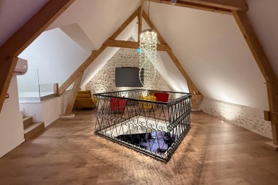 Vue aérienne d'une campagne verdoyante avec des champs, des arbres, une rivière et des habitations au loin.