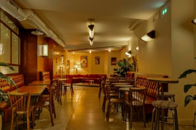 Table dressée dans un restaurant chaleureux avec planches de charcuterie, légumes, fromages, vin rouge et décor végétal.