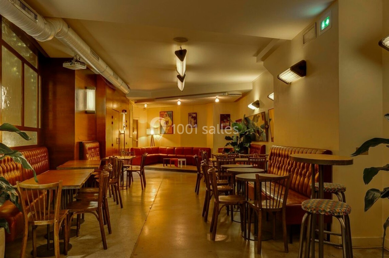 Salle de restaurant chaleureuse avec tables en bois, banquettes capitonnées et plantes décoratives.