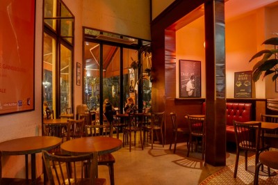 Table dressée dans un restaurant chaleureux avec planches de charcuterie, légumes, fromages, vin rouge et décor végétal.