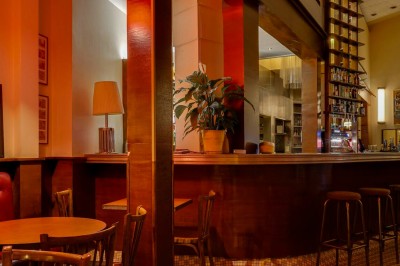 Table dressée dans un restaurant chaleureux avec planches de charcuterie, fromages, légumes et bouteilles de vin rouge.