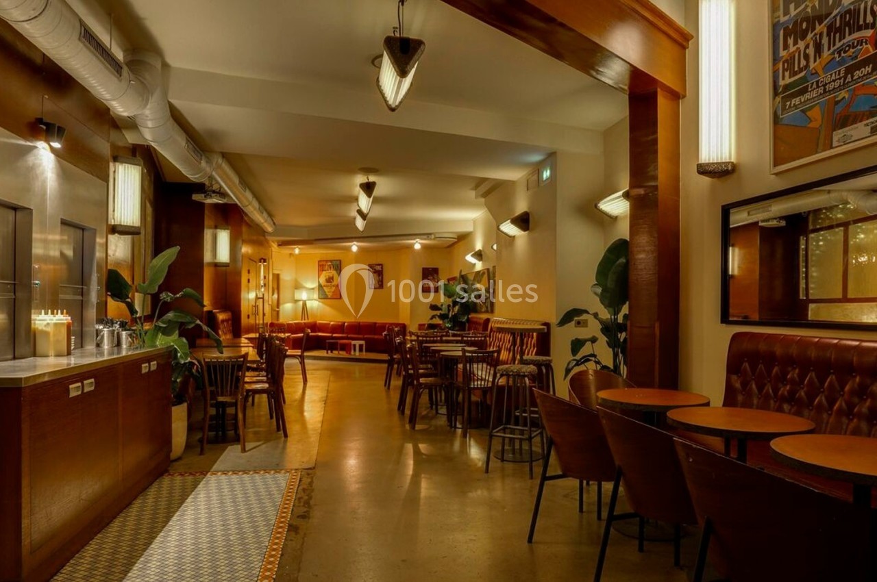 Salle de restaurant chaleureuse avec tables en bois, banquettes en cuir, plantes et éclairage tamisé.