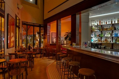 Table dressée dans un restaurant chaleureux avec planches de charcuterie, fromages, légumes et bouteilles de vin rouge.