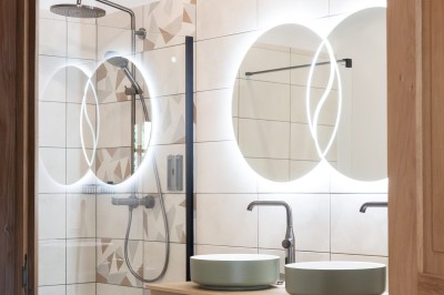 Chambre avec lit double, poutres apparentes, linge de lit blanc, et salle de bain attenante visible par une porte ouverte.