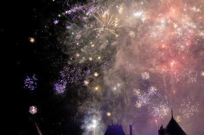 Chambre avec lit double, poutres apparentes, linge de lit blanc, et salle de bain attenante visible par une porte ouverte.