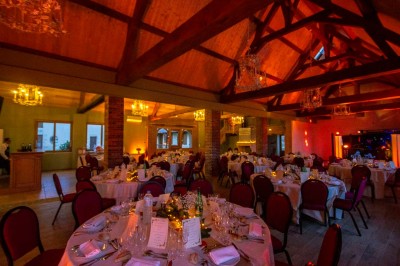 Chambre avec lit double, poutres apparentes, linge de lit blanc, et salle de bain attenante visible par une porte ouverte.