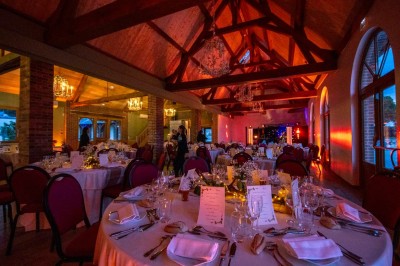 Chambre avec lit double, poutres apparentes, linge de lit blanc, et salle de bain attenante visible par une porte ouverte.