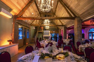 Chambre avec lit double, poutres apparentes, linge de lit blanc, et salle de bain attenante visible par une porte ouverte.