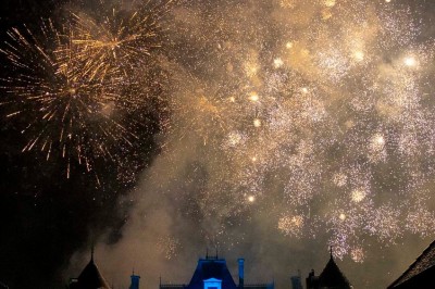Chambre avec lit double, poutres apparentes, linge de lit blanc, et salle de bain attenante visible par une porte ouverte.