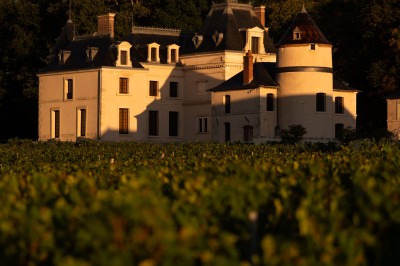 Groupe de musiciens en uniforme rouge jouant devant un bâtiment éclairé de nuit, avec une tente blanche au centre.