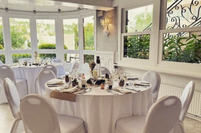 Buffet décoré avec des ballons roses et blancs, plats variés, et un cochon rôti sur une table drapée de blanc.