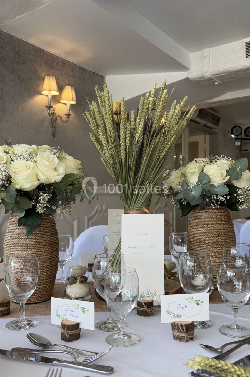 Table de réception décorée avec des bouquets de fleurs blanches, épis de blé et marque-places personnalisés.