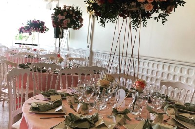 Buffet décoré avec des ballons roses et blancs, plats variés, et un cochon rôti sur une table drapée de blanc.