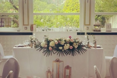 Buffet décoré avec des ballons roses et blancs, plats variés, et un cochon rôti sur une table drapée de blanc.