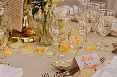Buffet décoré avec des ballons roses et blancs, plats variés, et un cochon rôti sur une table drapée de blanc.